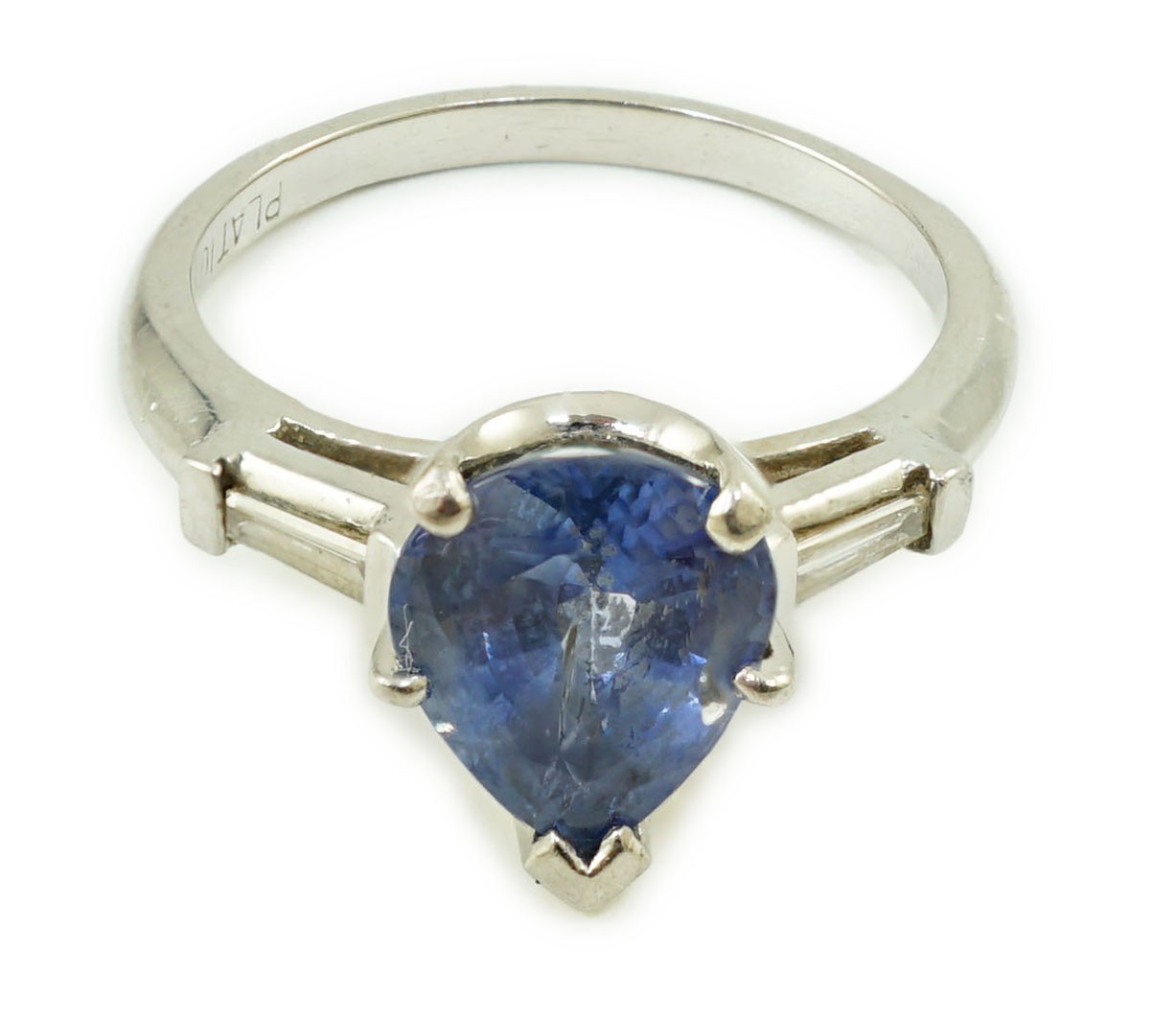 A platinum (10%) and single stone pear cut Ceylon sapphire set ring, with tapered baguette cut diamond set shoulders
